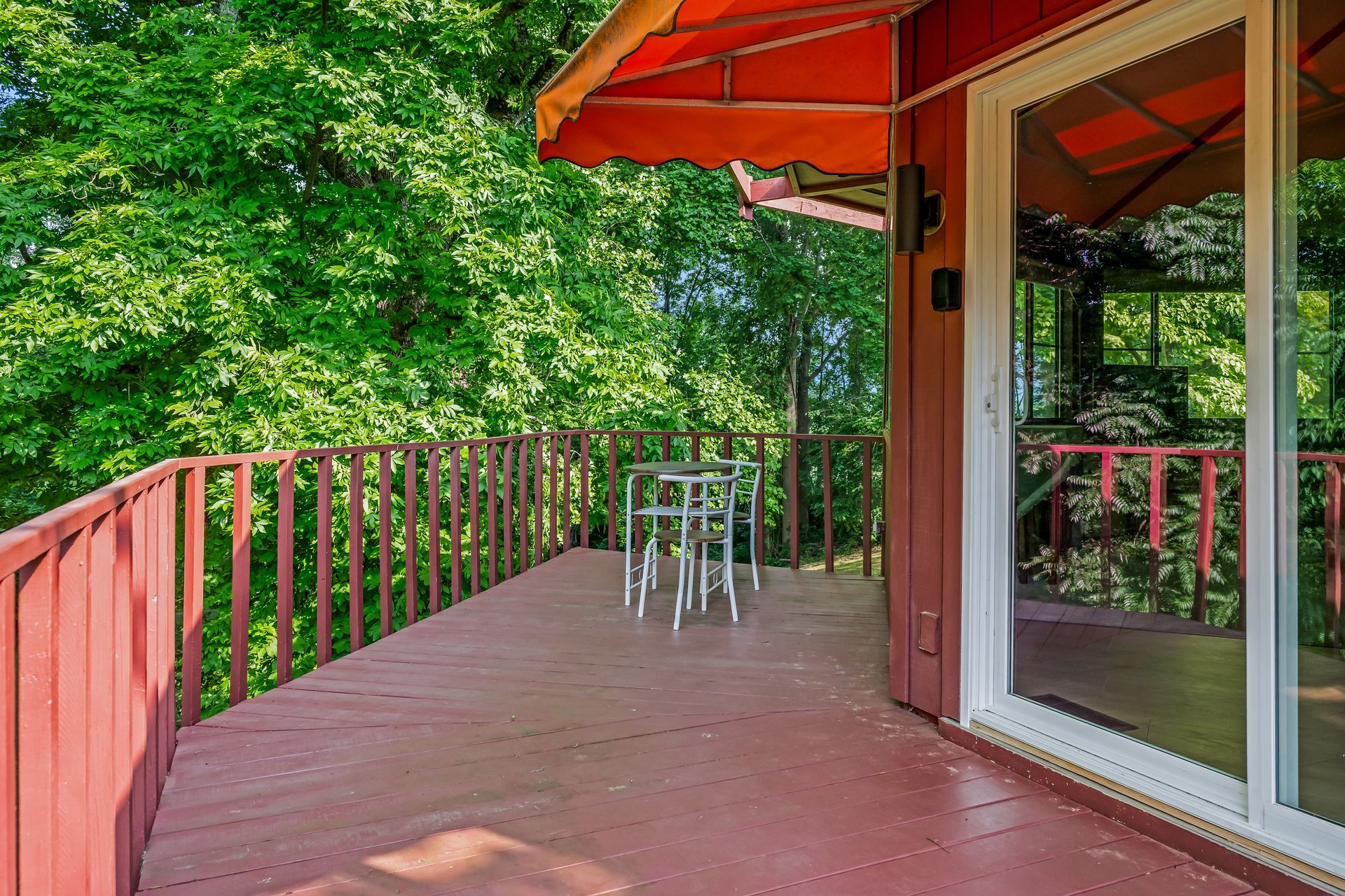 A red deck with a table and chairs under an orange awning