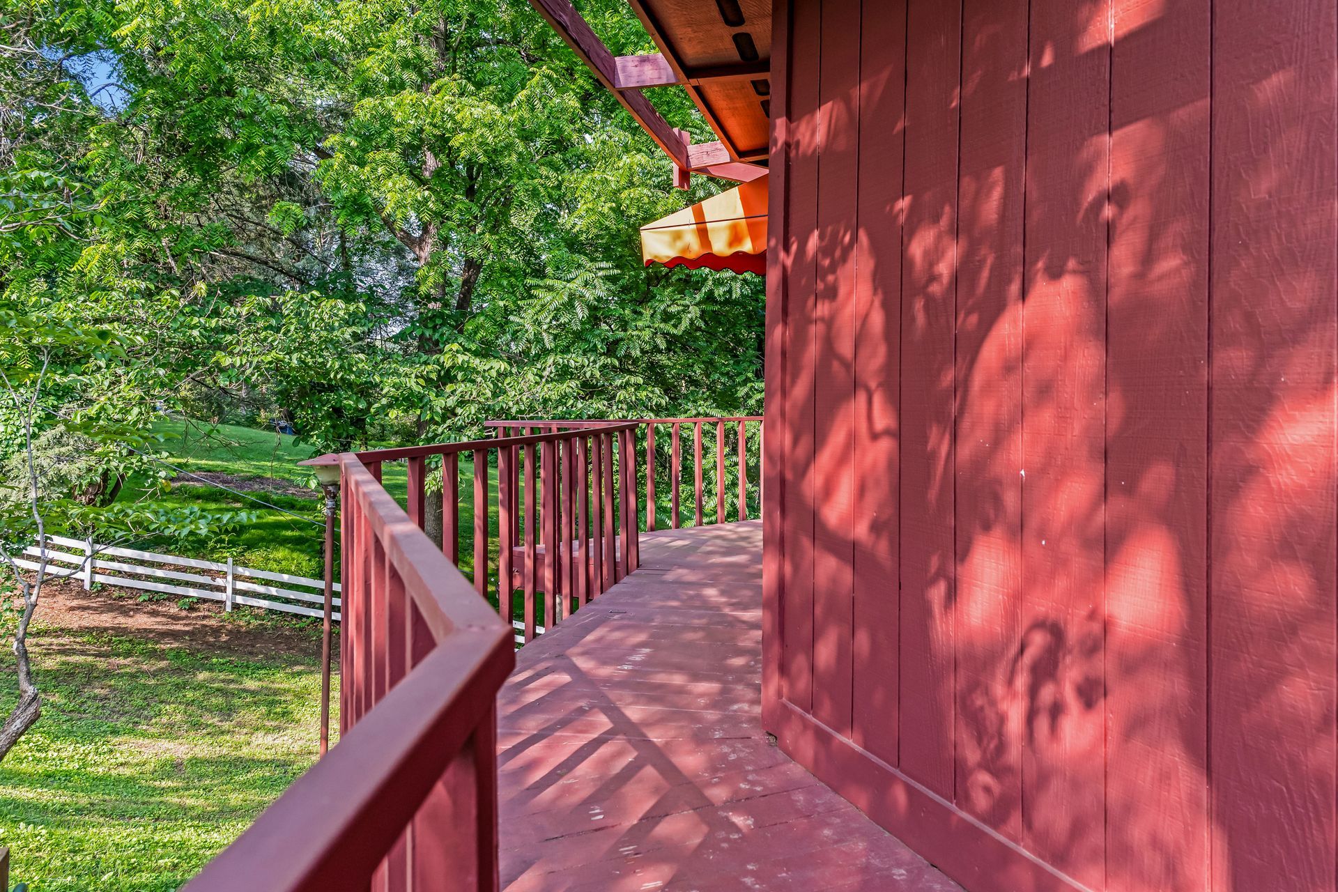 A red building with a wooden walkway leading to it surrounded by trees.