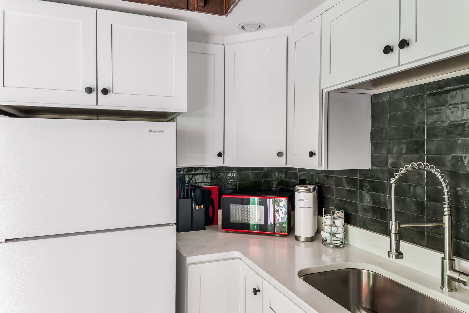 A kitchen with white cabinets , a refrigerator , a sink , and a microwave.
