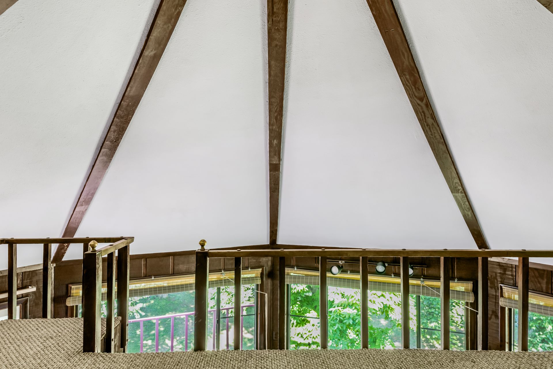 A balcony with a wooden railing and a white ceiling