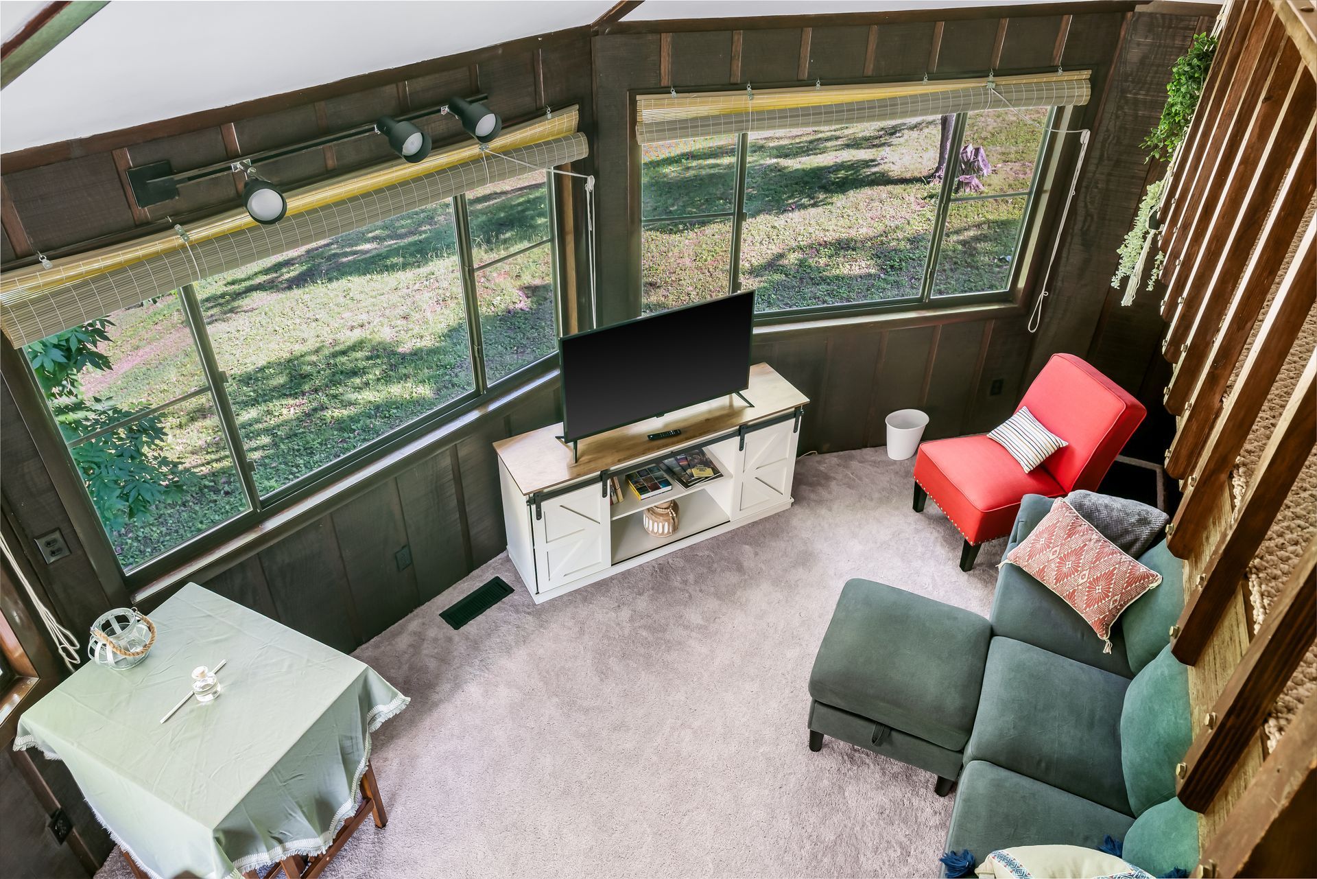 An aerial view of a living room with a couch , chair , table and television.