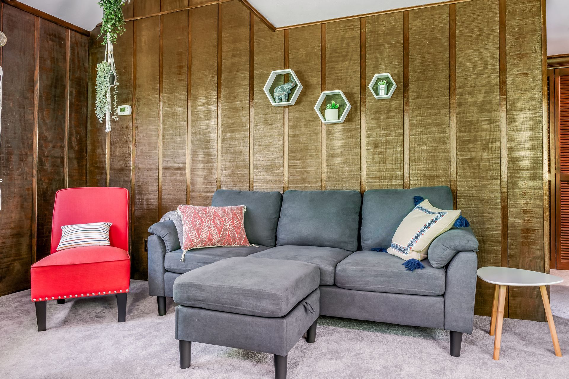 A living room with a couch , chairs , ottoman and table.