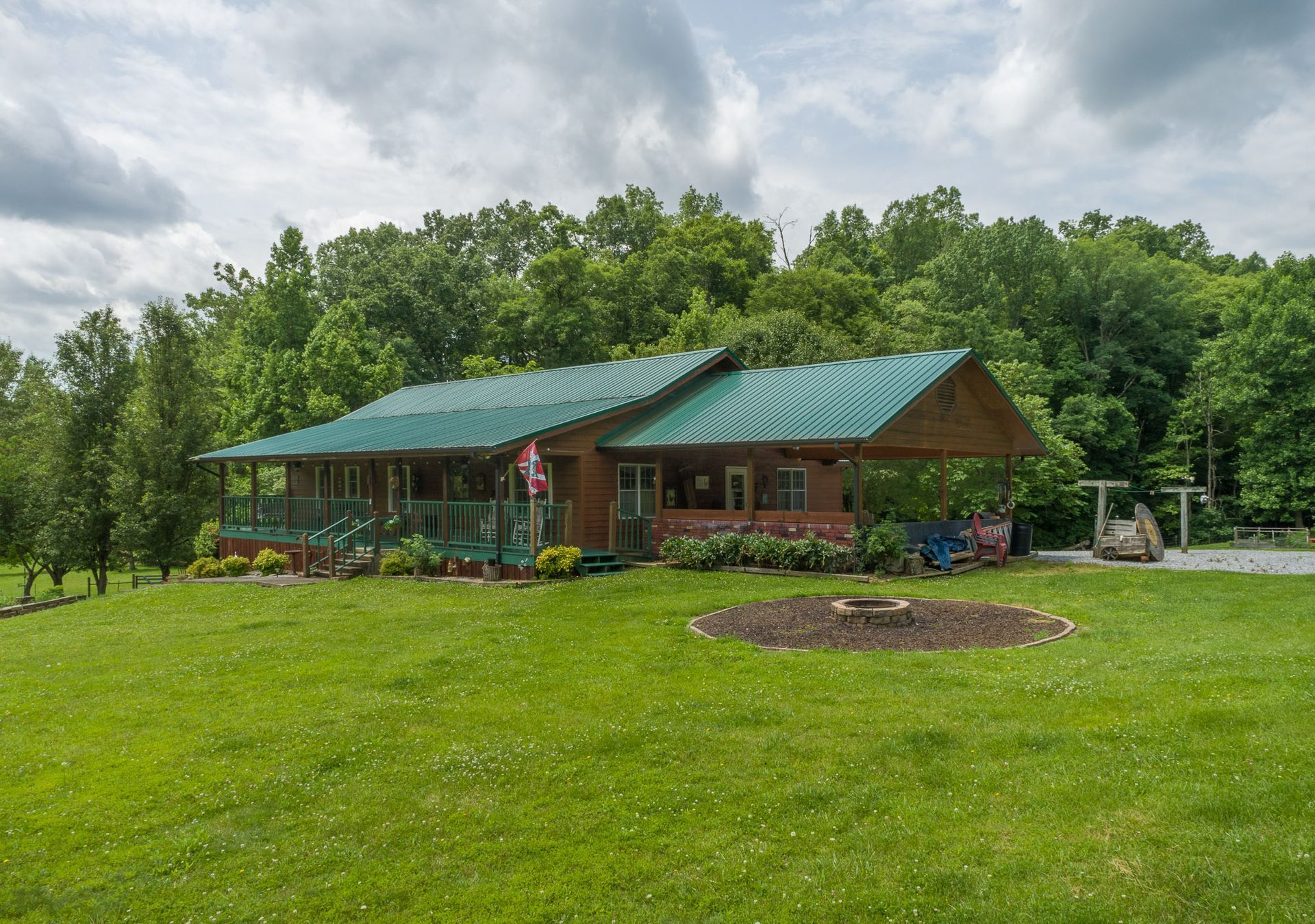 A large house with a green roof is sitting in the middle of a lush green field.