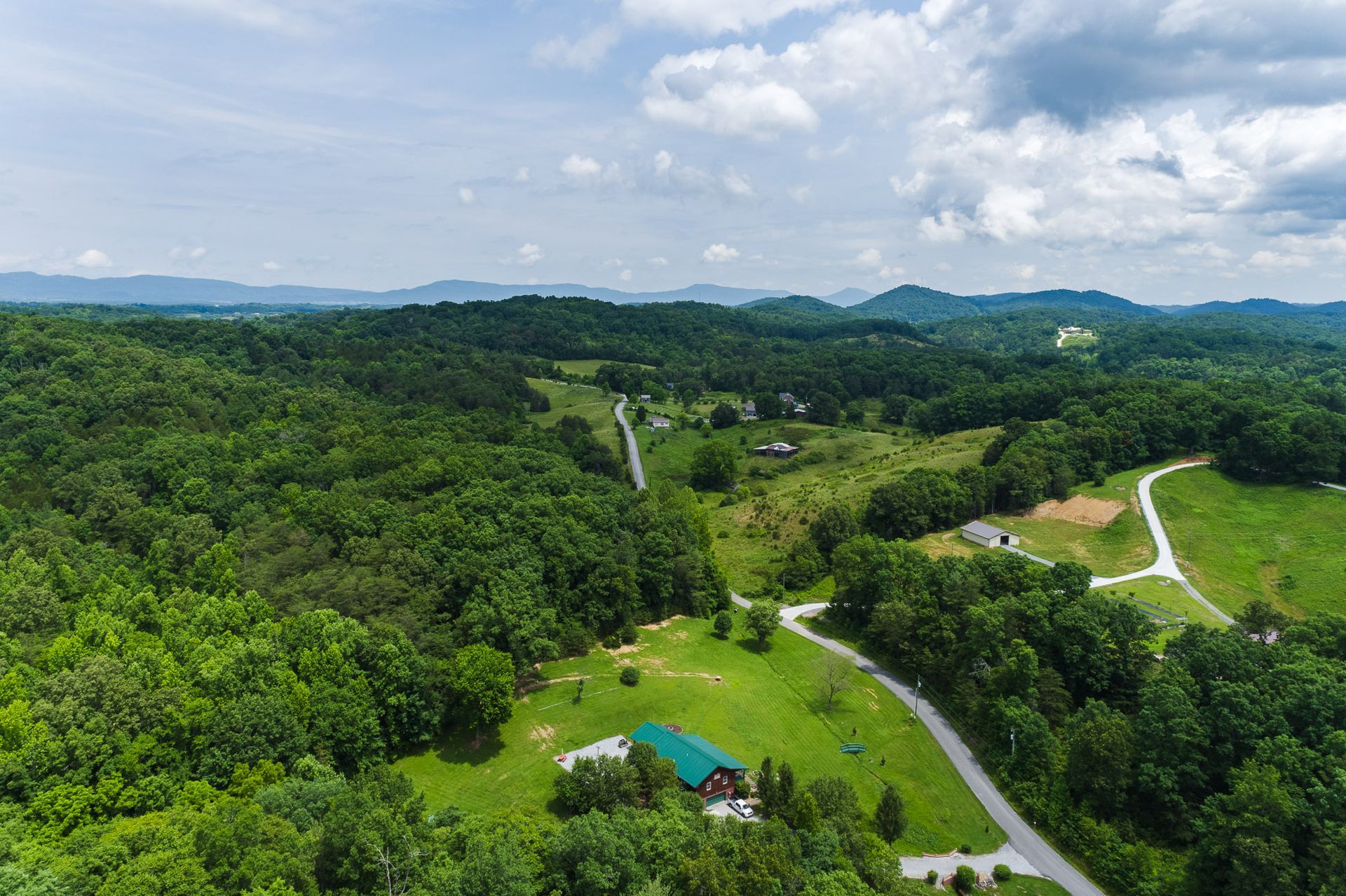 An aerial view of a house in the middle of a lush green forest.