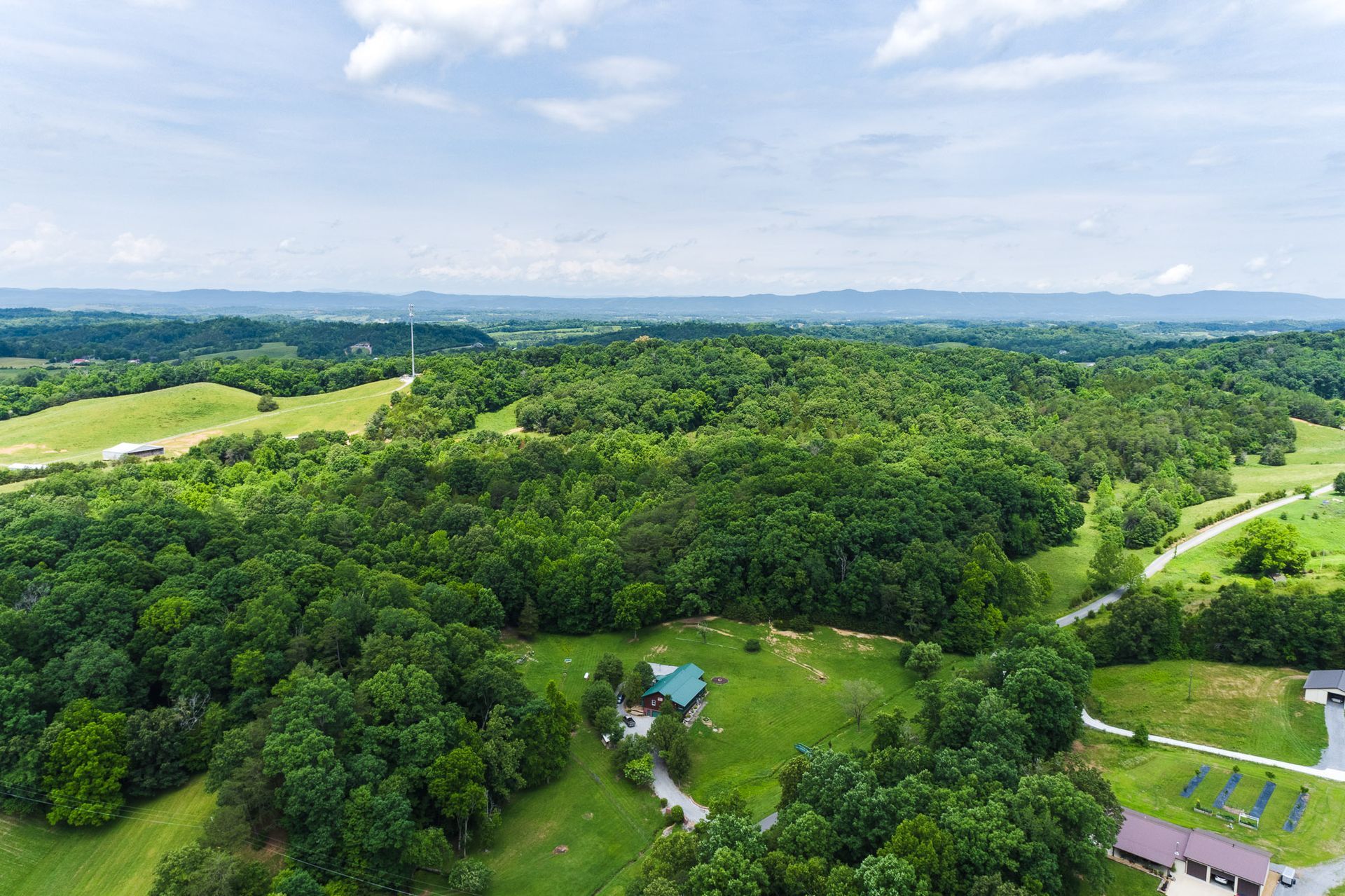 An aerial view of a house in the middle of a lush green forest.