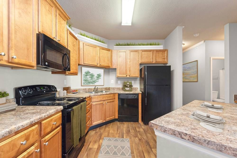 Kitchen with wooden cabinets , a black refrigerator , a stove , and a microwave.