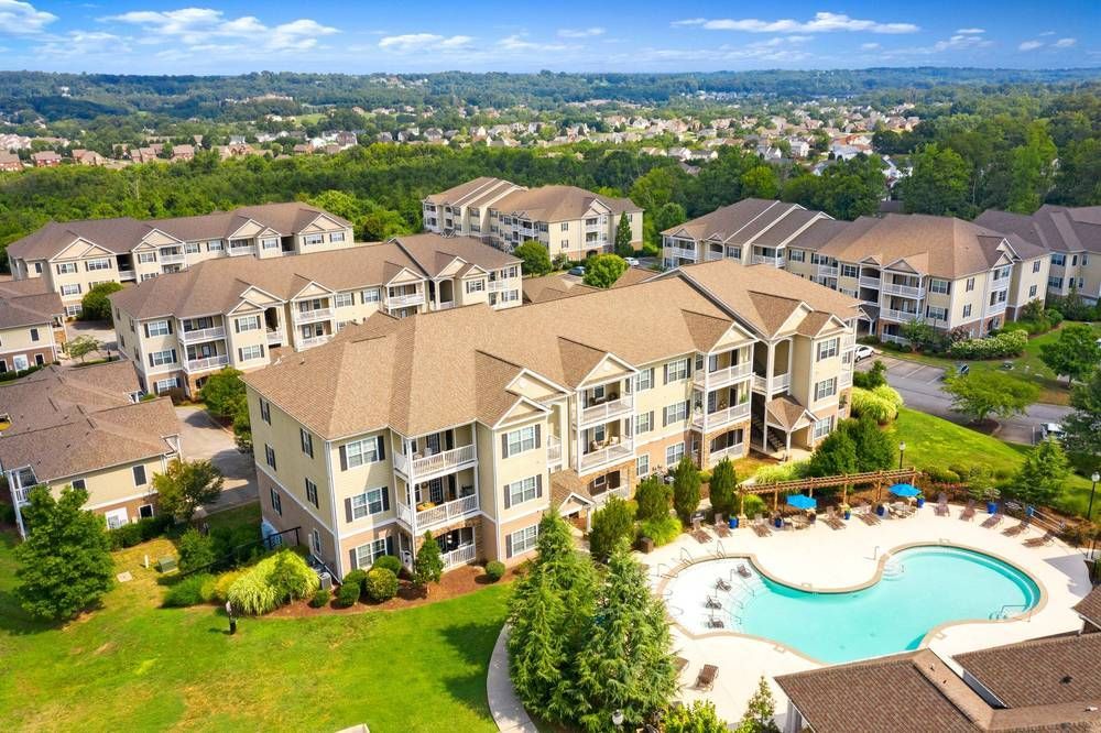 Aerial view of a large apartment complex with a large swimming pool in the middle.