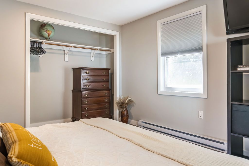 Fully furnished bedroom with a bed , dresser , and window in Mystic, CT