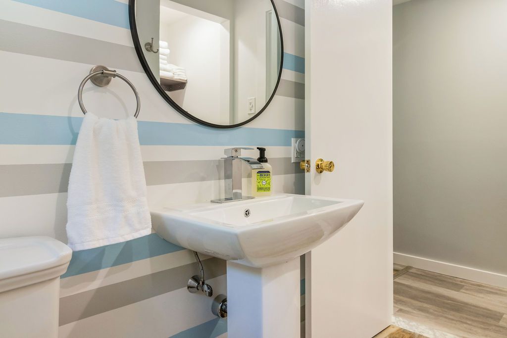 Fully equipped bathroom with a sink , toilet , mirror and striped wall in Mystic, CT