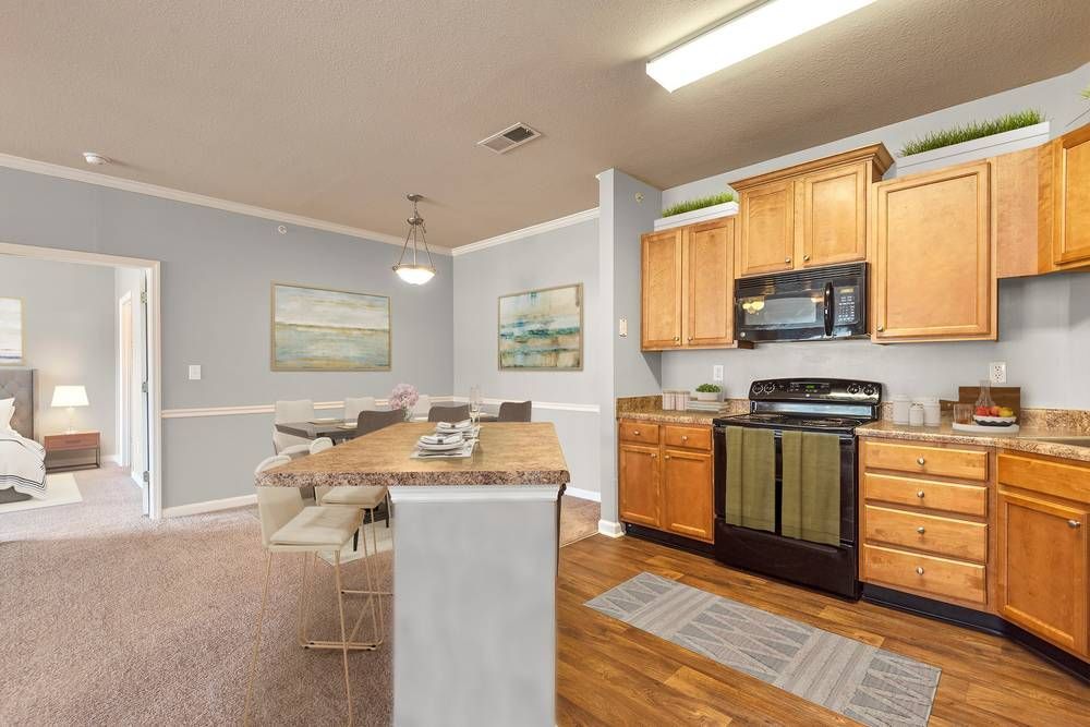 Kitchen with wooden cabinets , a stove , a microwave , and a table.