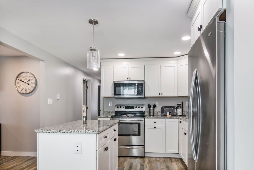 Modern kitchen with white cabinets , stainless steel appliances , granite counter tops and a clock on the wall in Mystic, CT.