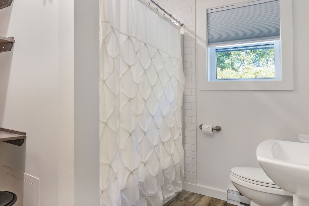 Bathroom with a shower curtain , toilet , sink and window Mystic, CT