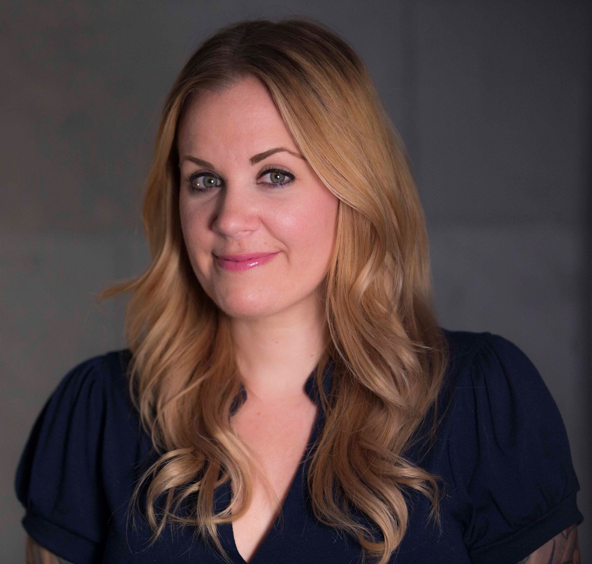 A woman with long blonde hair is wearing a blue shirt