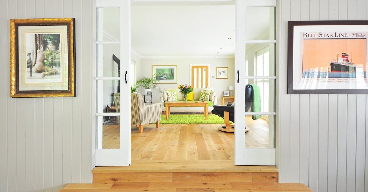 Open doorway leading to a brightly lit living room with wood floors and a green rug.
