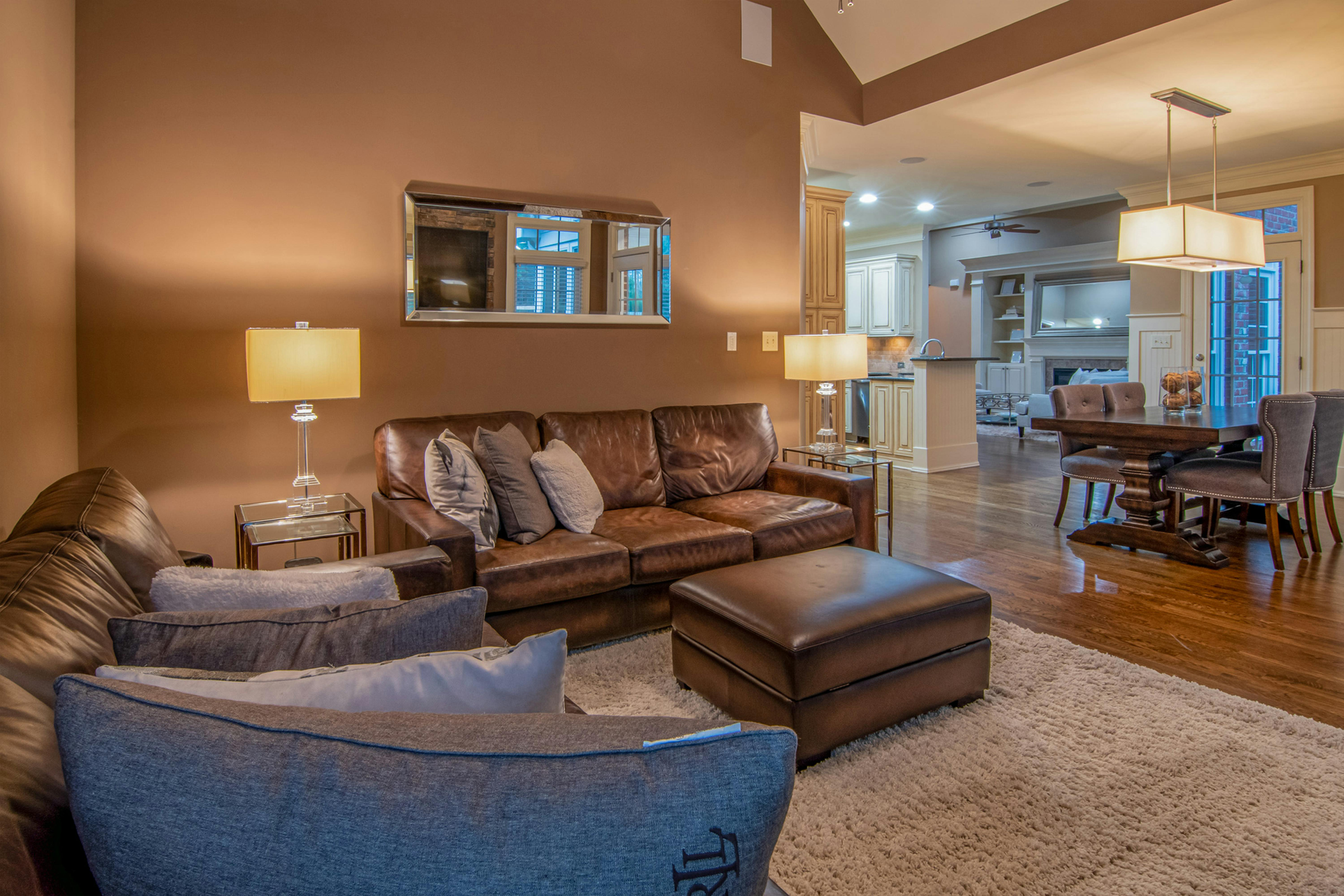 A living room with a couch , chairs , ottoman and lamps.