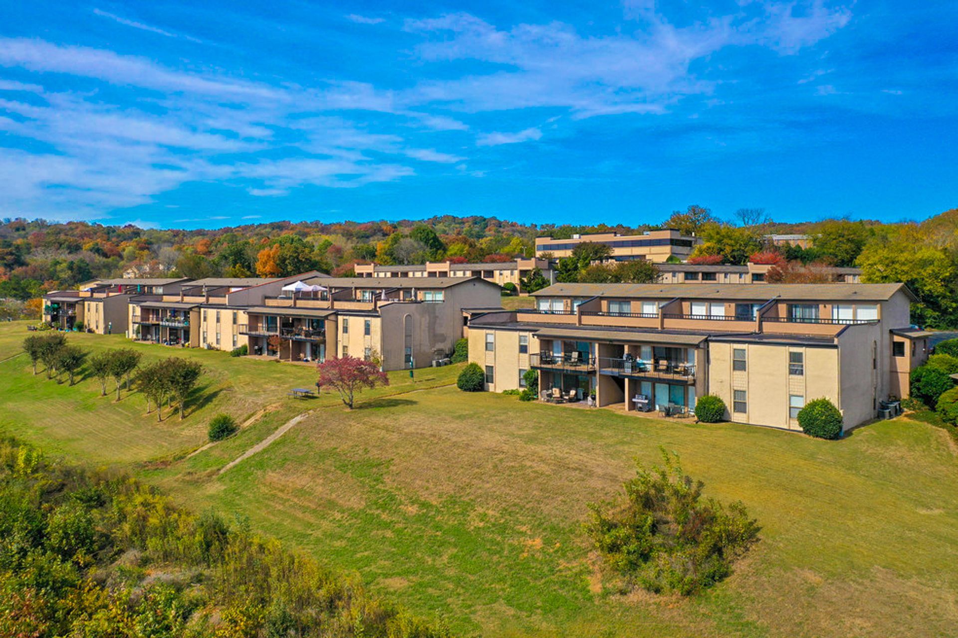 An aerial view of a row of apartment buildings sitting on top of a grassy hill.