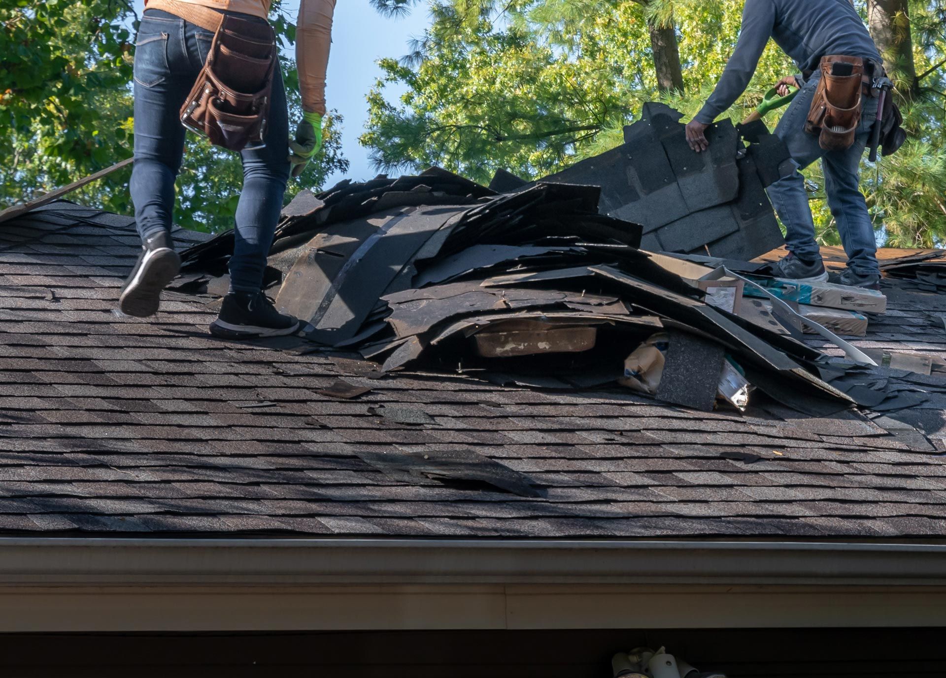 Roof replacement workers removing old shingles during residential repair.