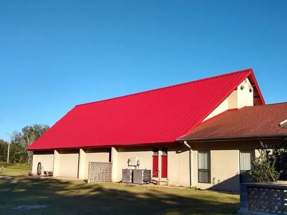 A house with a red roof and a blue sky in the background