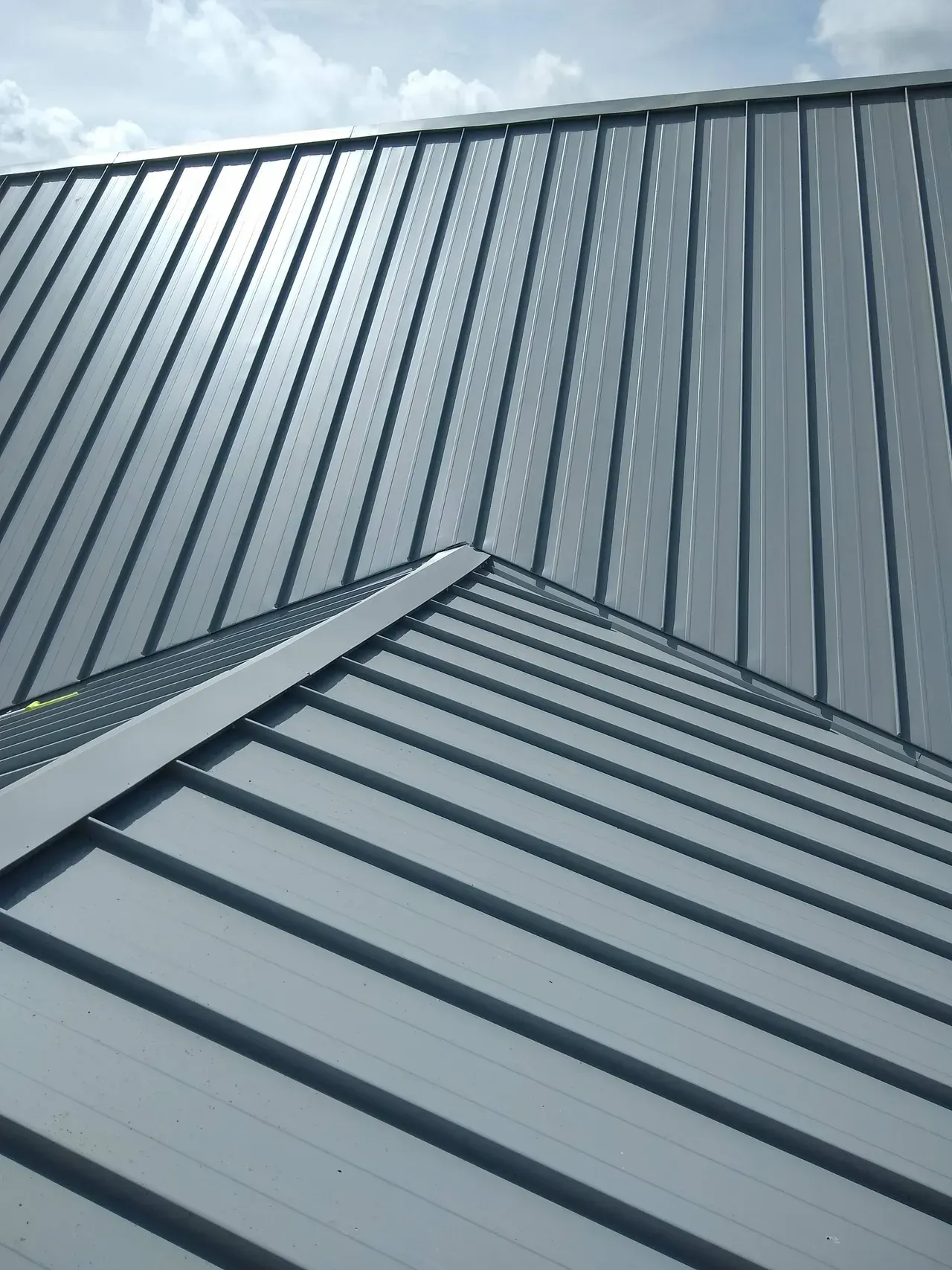 A close up of a metal roof with a blue sky in the background.
