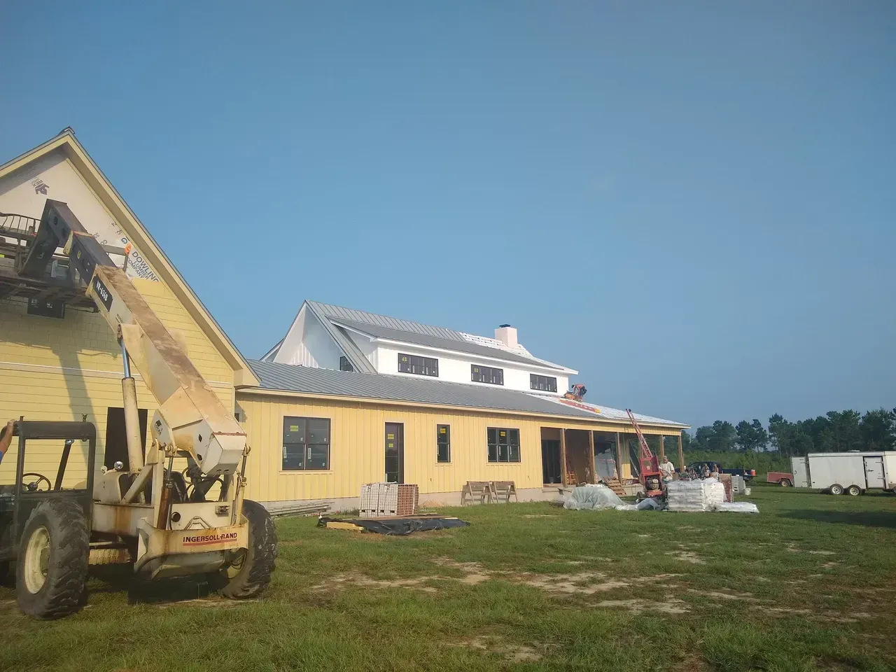 A tractor is parked in front of a house under construction