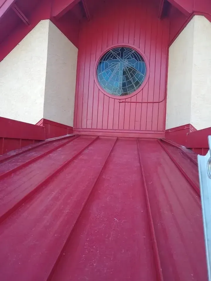 A red building with a stained glass window and a red roof.