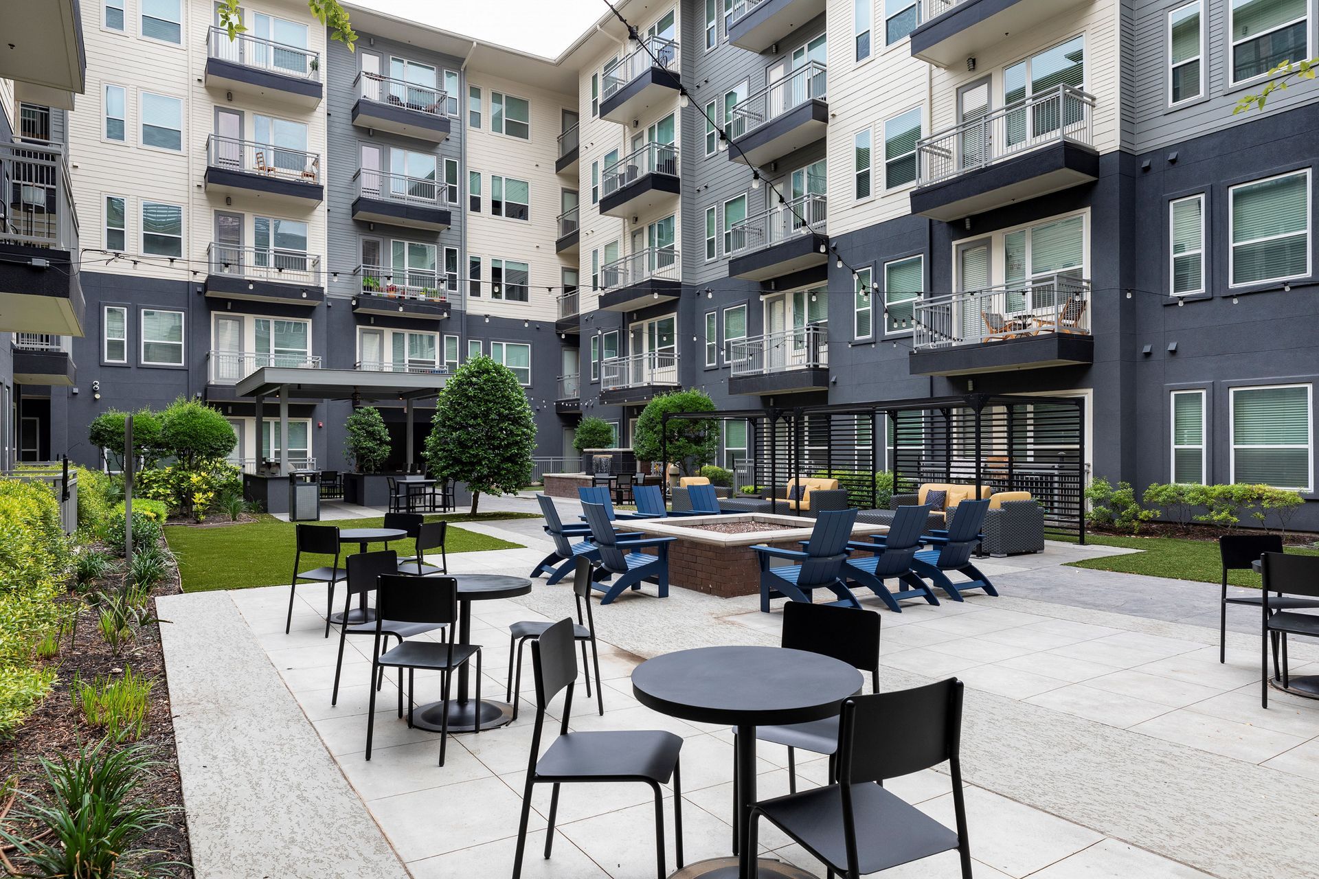 A large apartment building with tables and chairs in front of it.