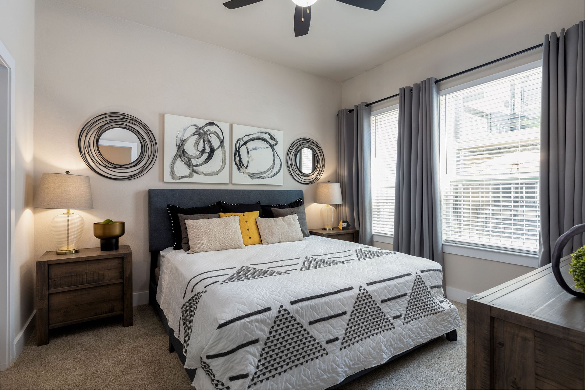 A bedroom with a bed , nightstand , lamps and a ceiling fan.