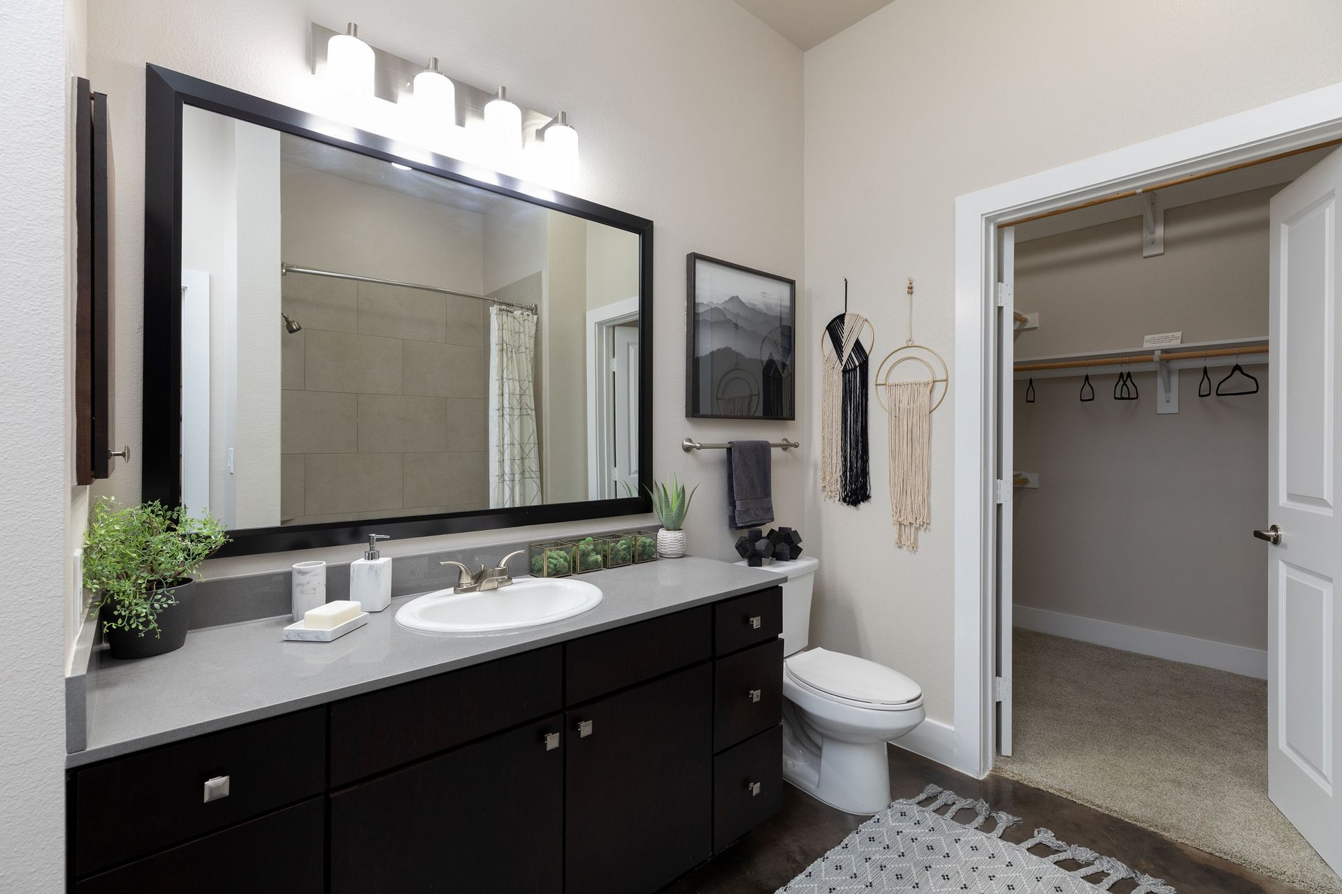 A bathroom with a sink , toilet , mirror and walk in closet.