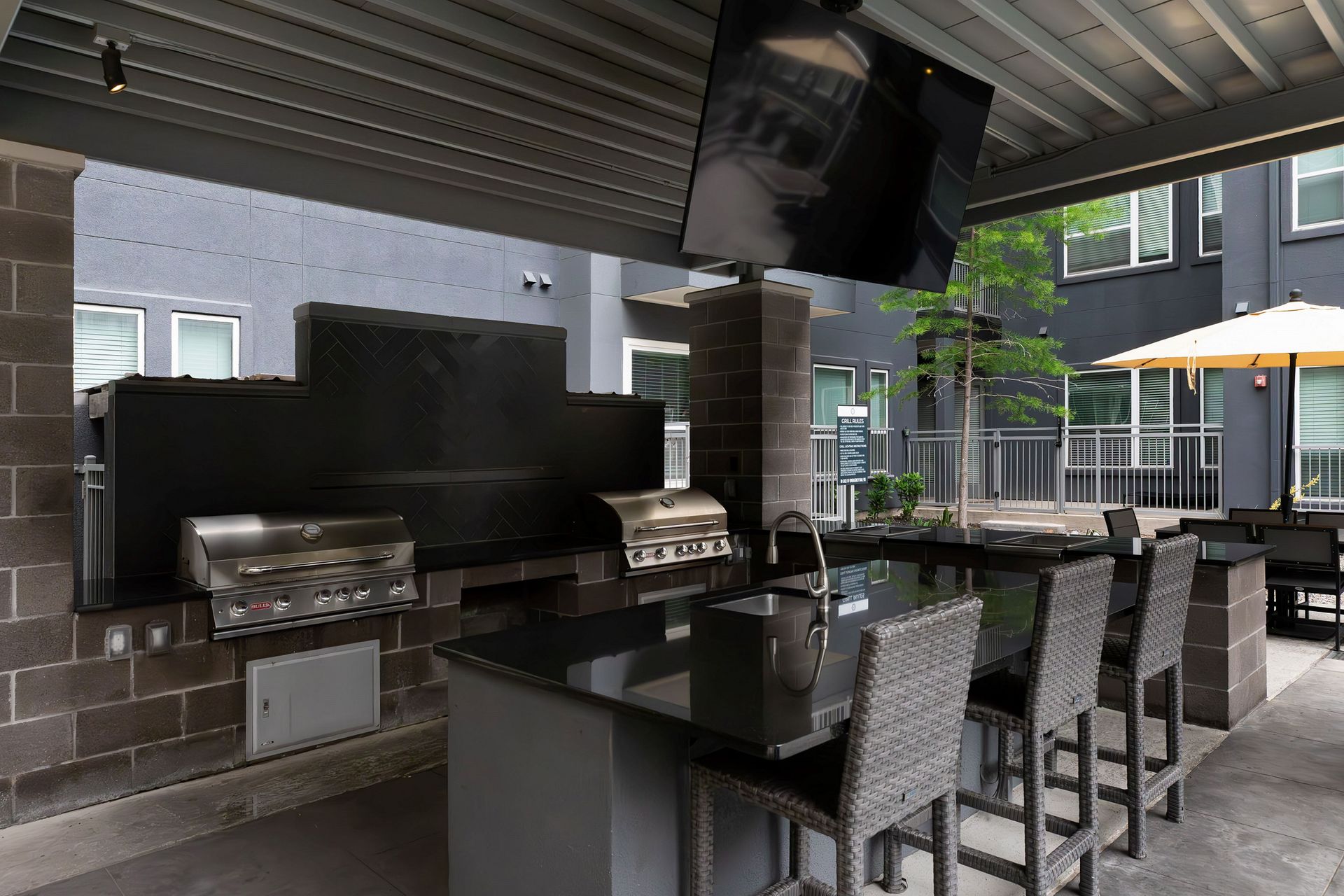A patio area with a grill and a television hanging from the ceiling.