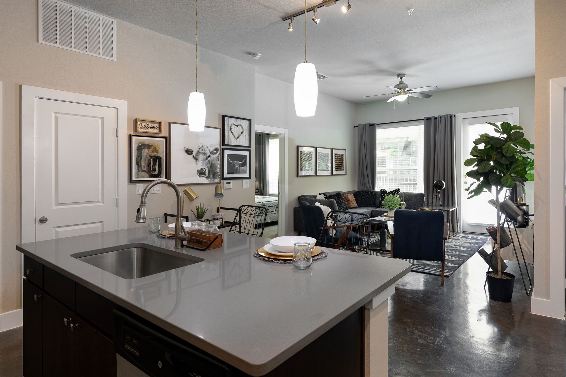 A kitchen with a sink and a living room in the background