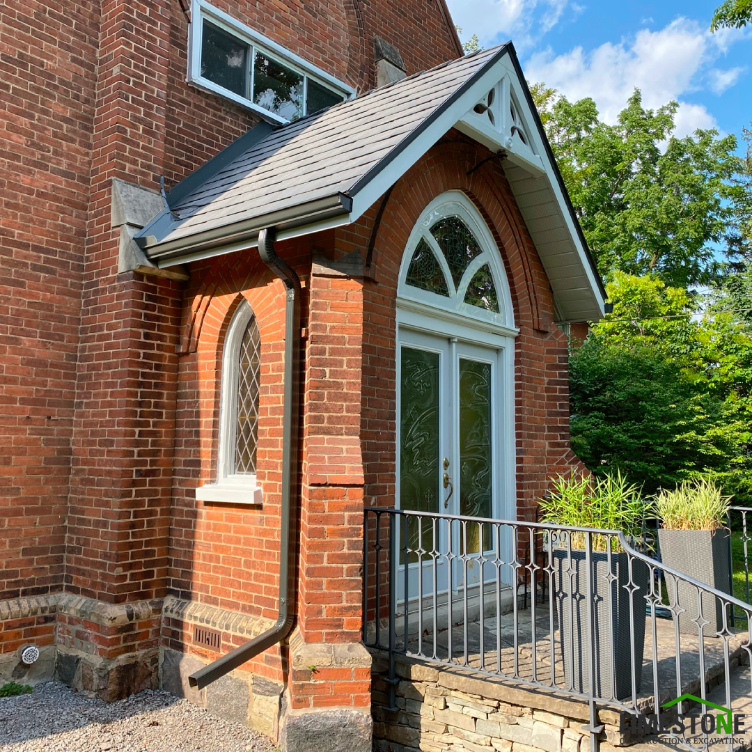 A brick building with a porch and stairs leading to it.