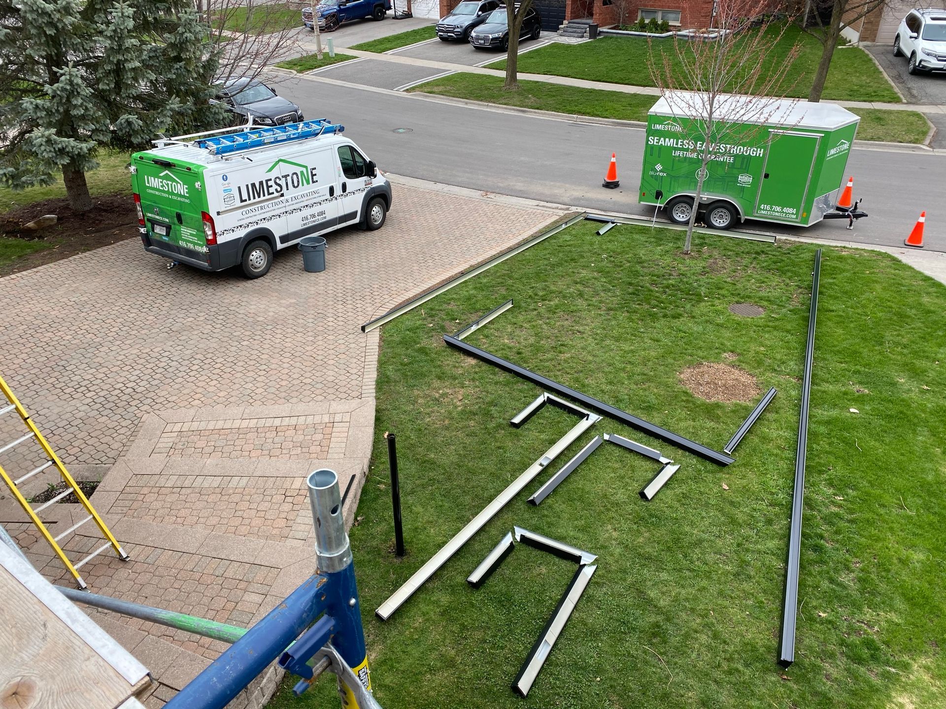 A green and white van is parked in a driveway next to a trailer.