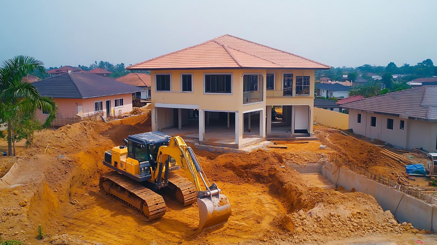 An excavator is digging a hole in front of a house under construction.