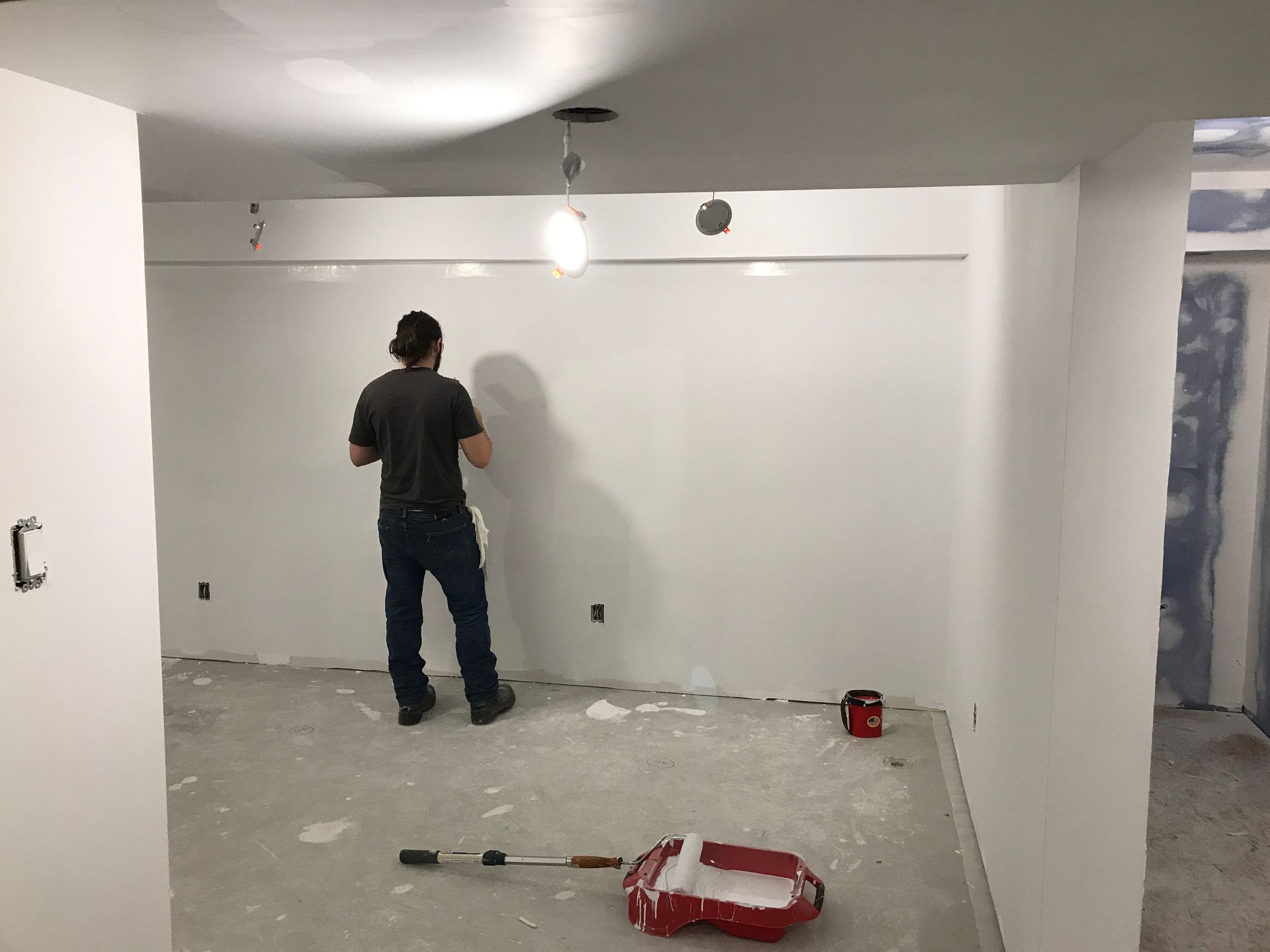 a man is standing in a room painting a wall .