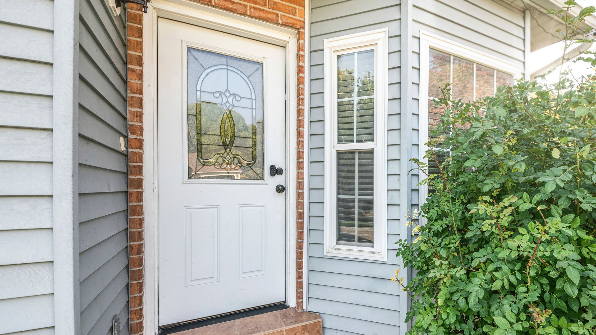A white door with a glass window is on the side of a house.