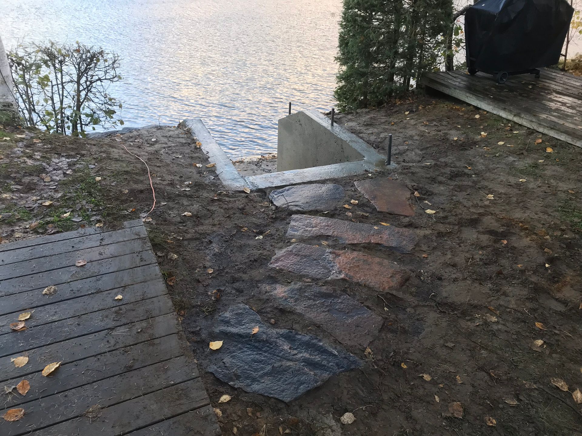 a stone walkway leading to a lake next to a wooden deck .