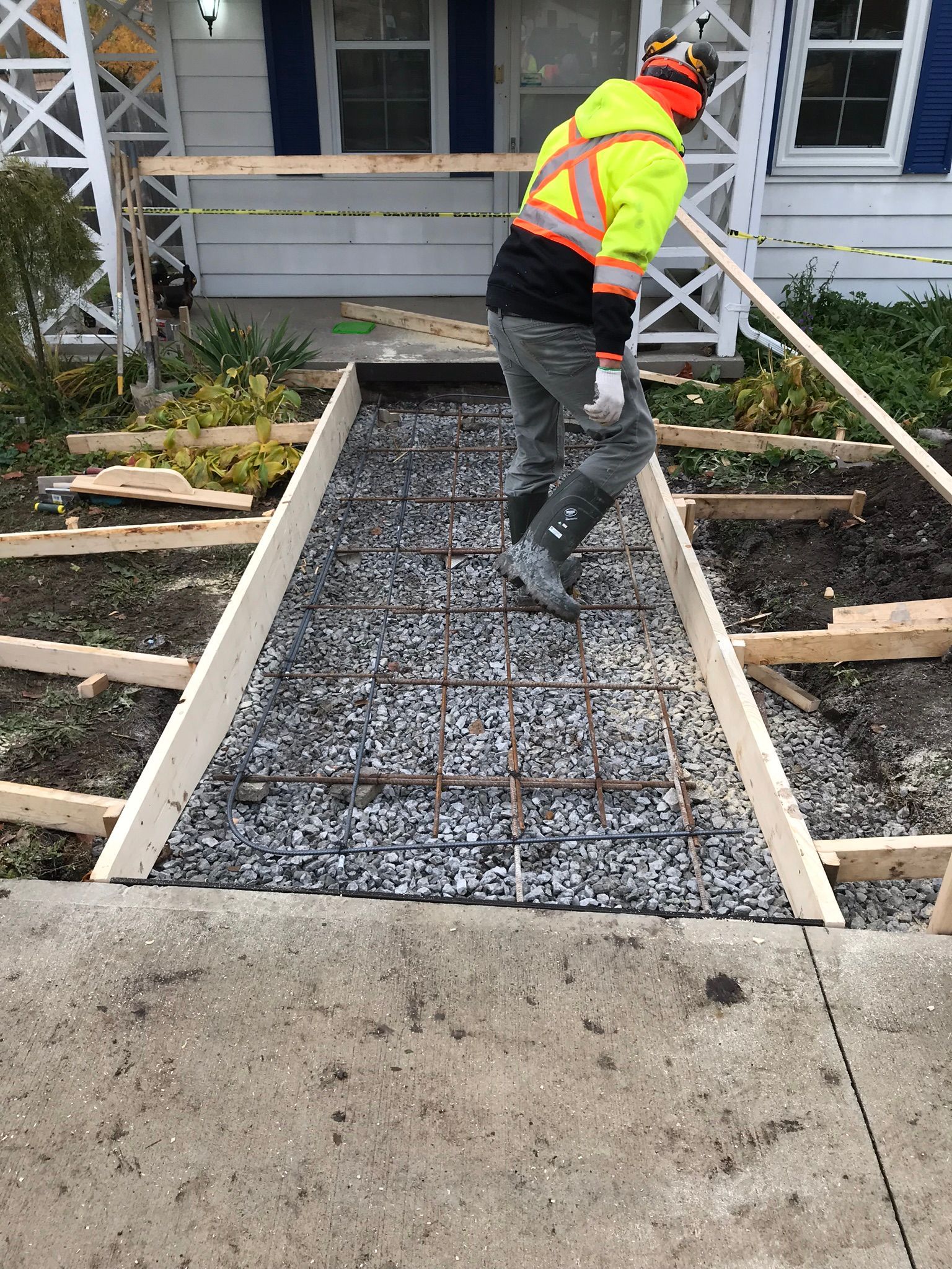 a man is laying concrete on a sidewalk in front of a house .