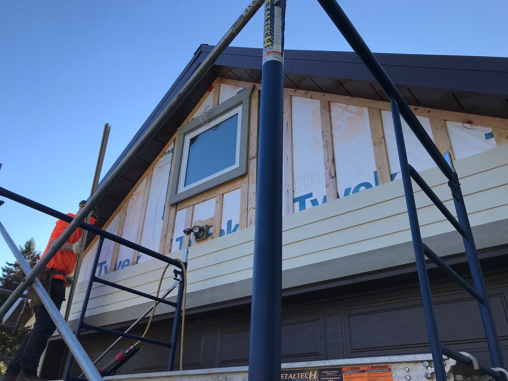 a man is standing on a scaffolding on the side of a house .