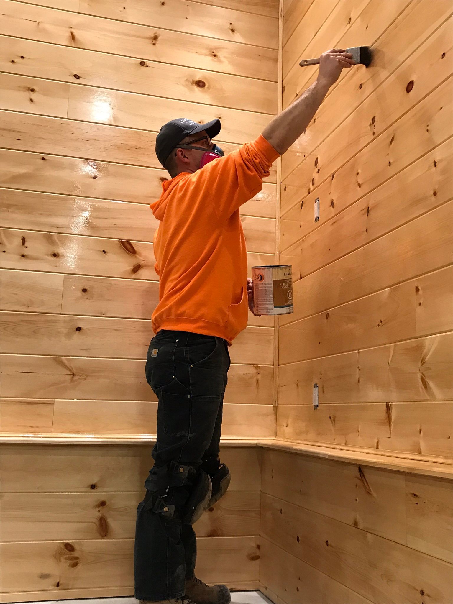 a man is painting a wooden wall with a brush .
