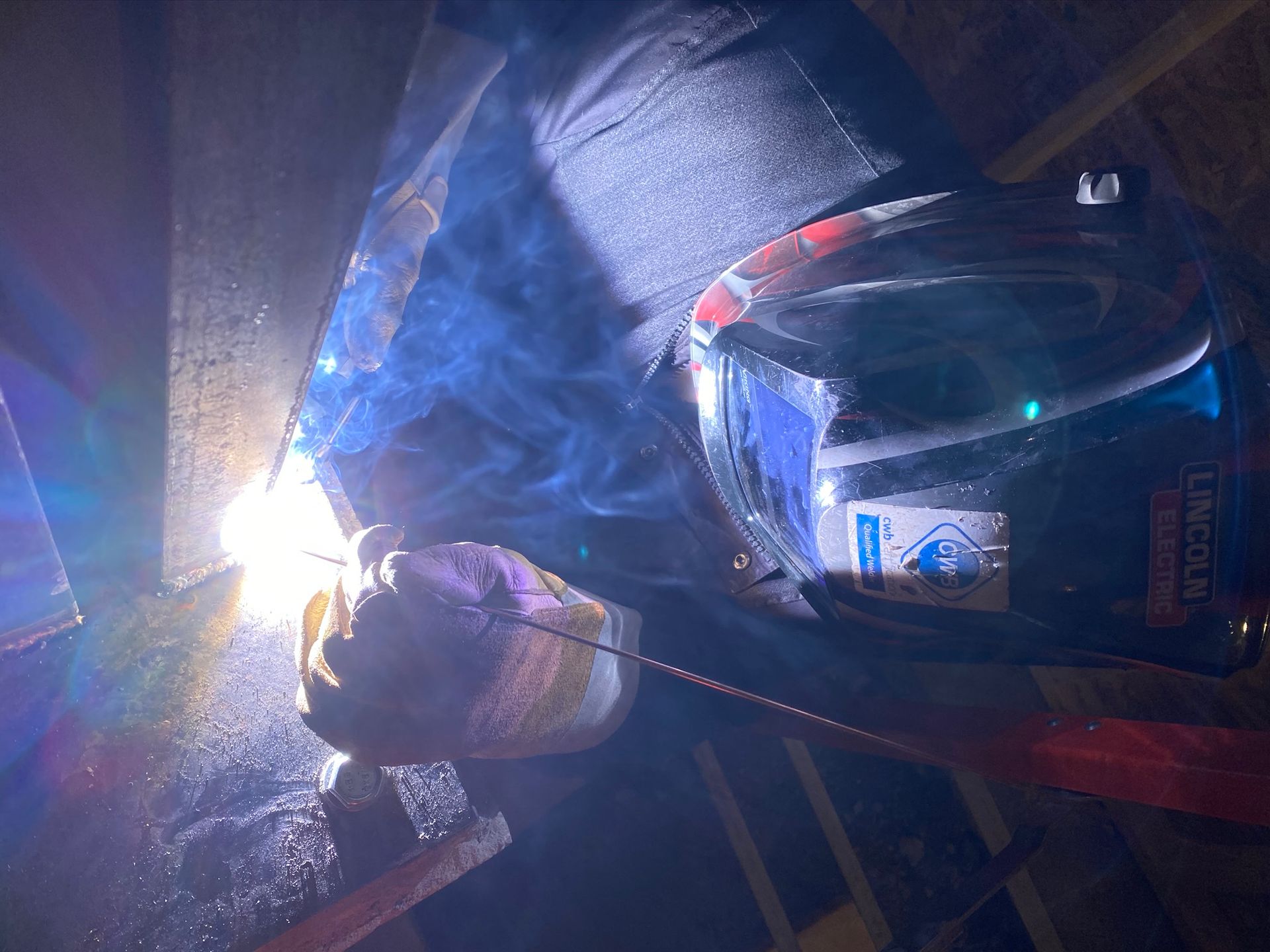a man is welding a piece of metal in a dark room .