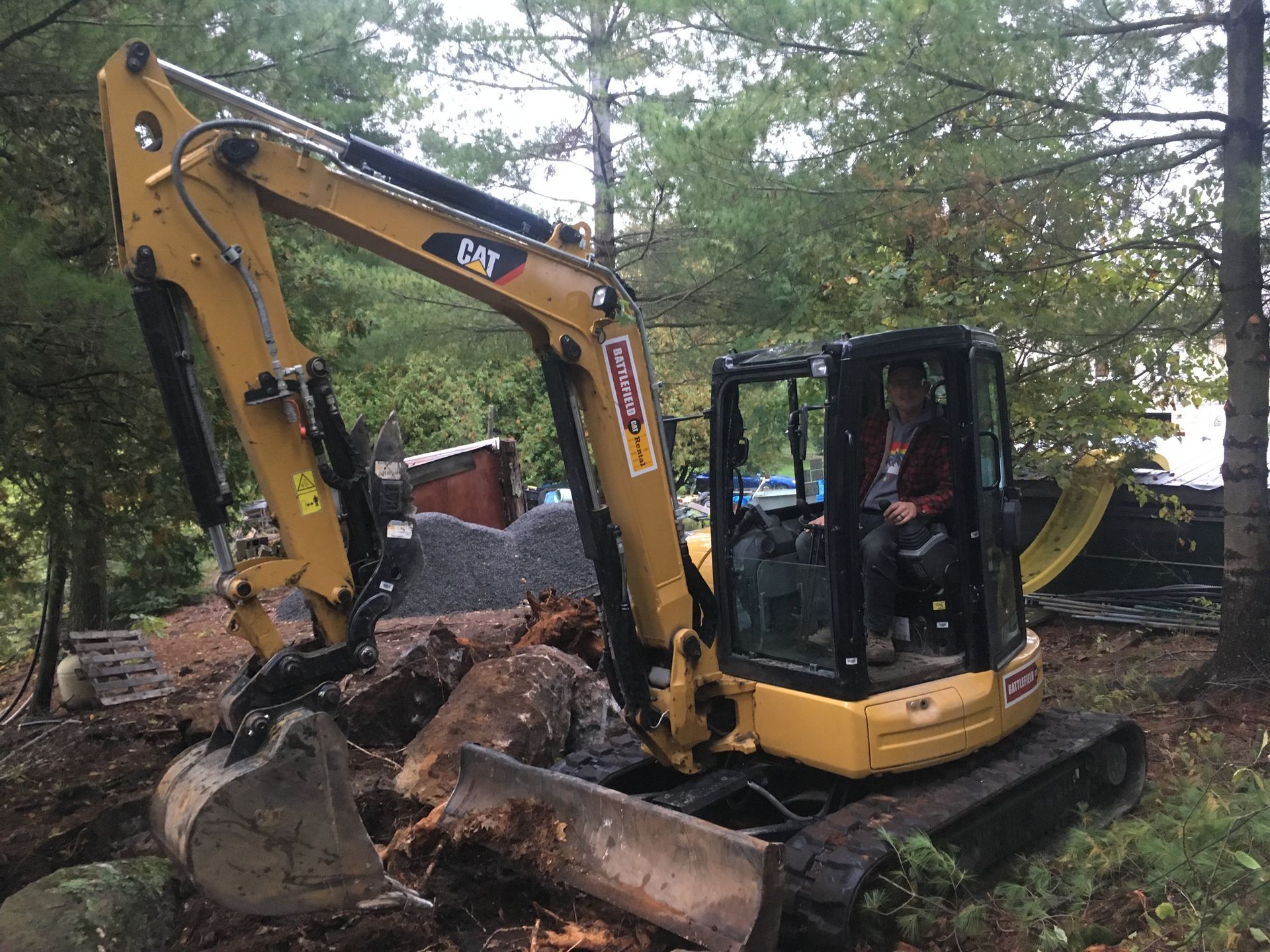 a man is sitting in the driver 's seat of a cat excavator .