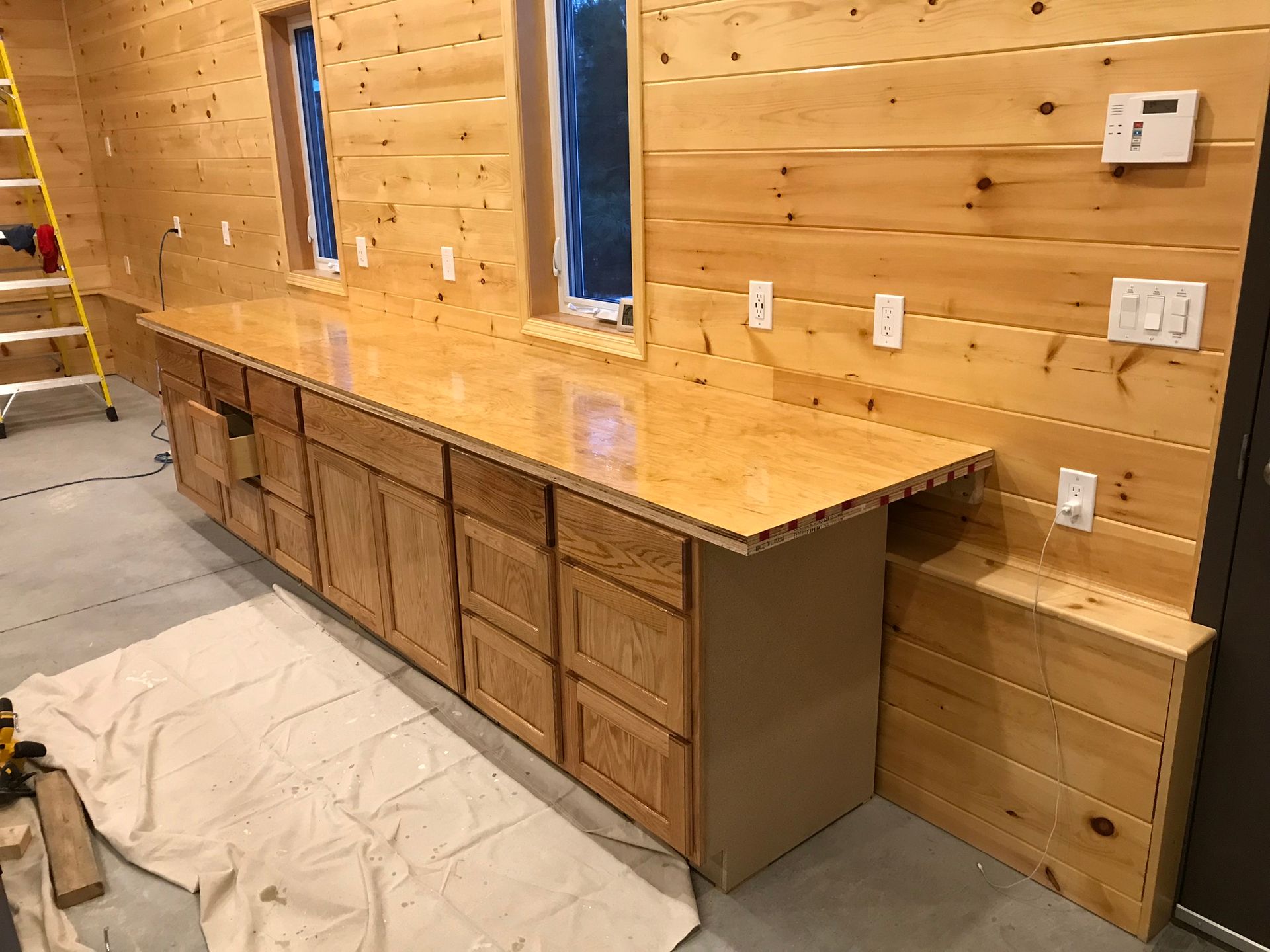 a long wooden counter with drawers and cabinets in a room with wooden walls .