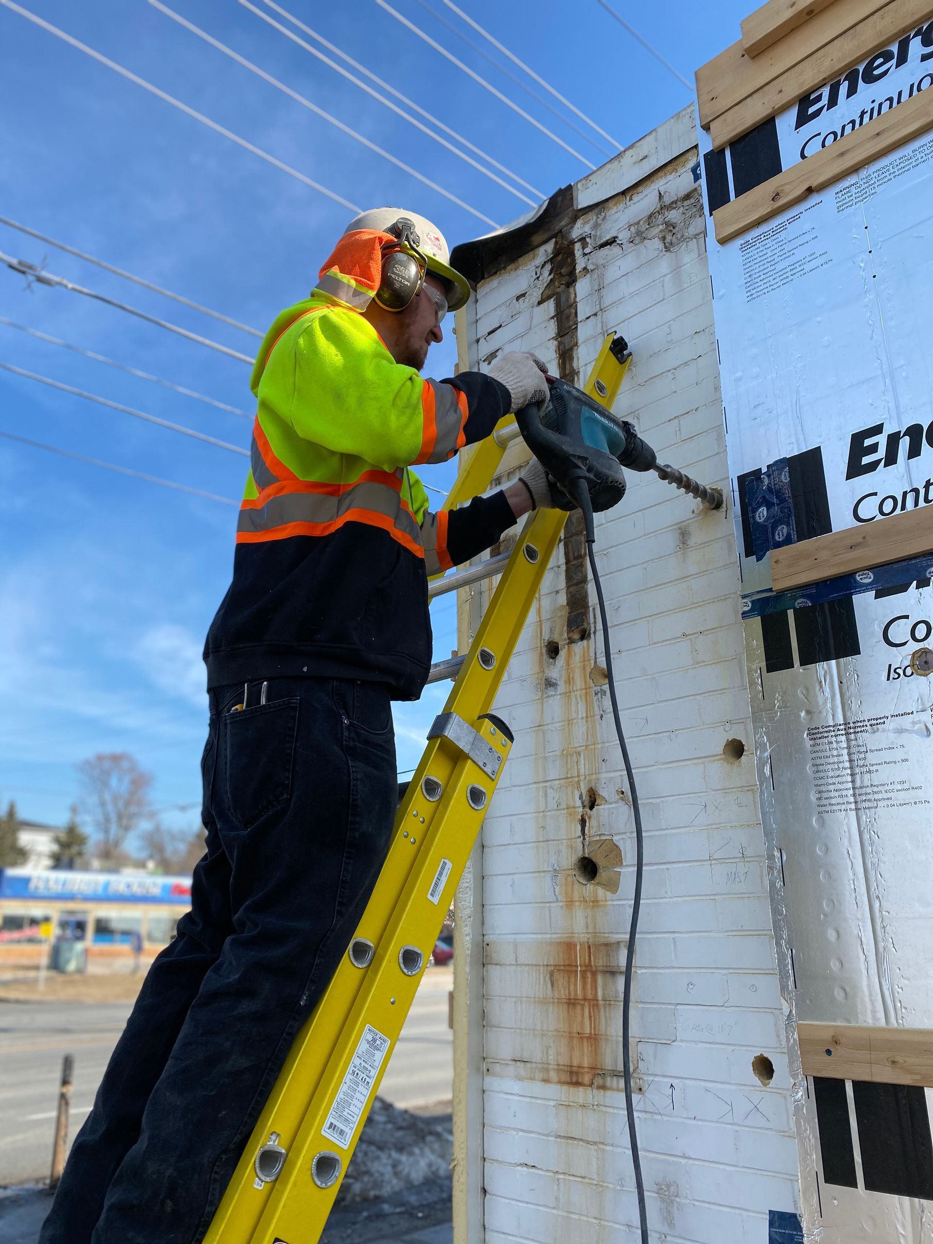 a man on a ladder is working on a wall with a hammer