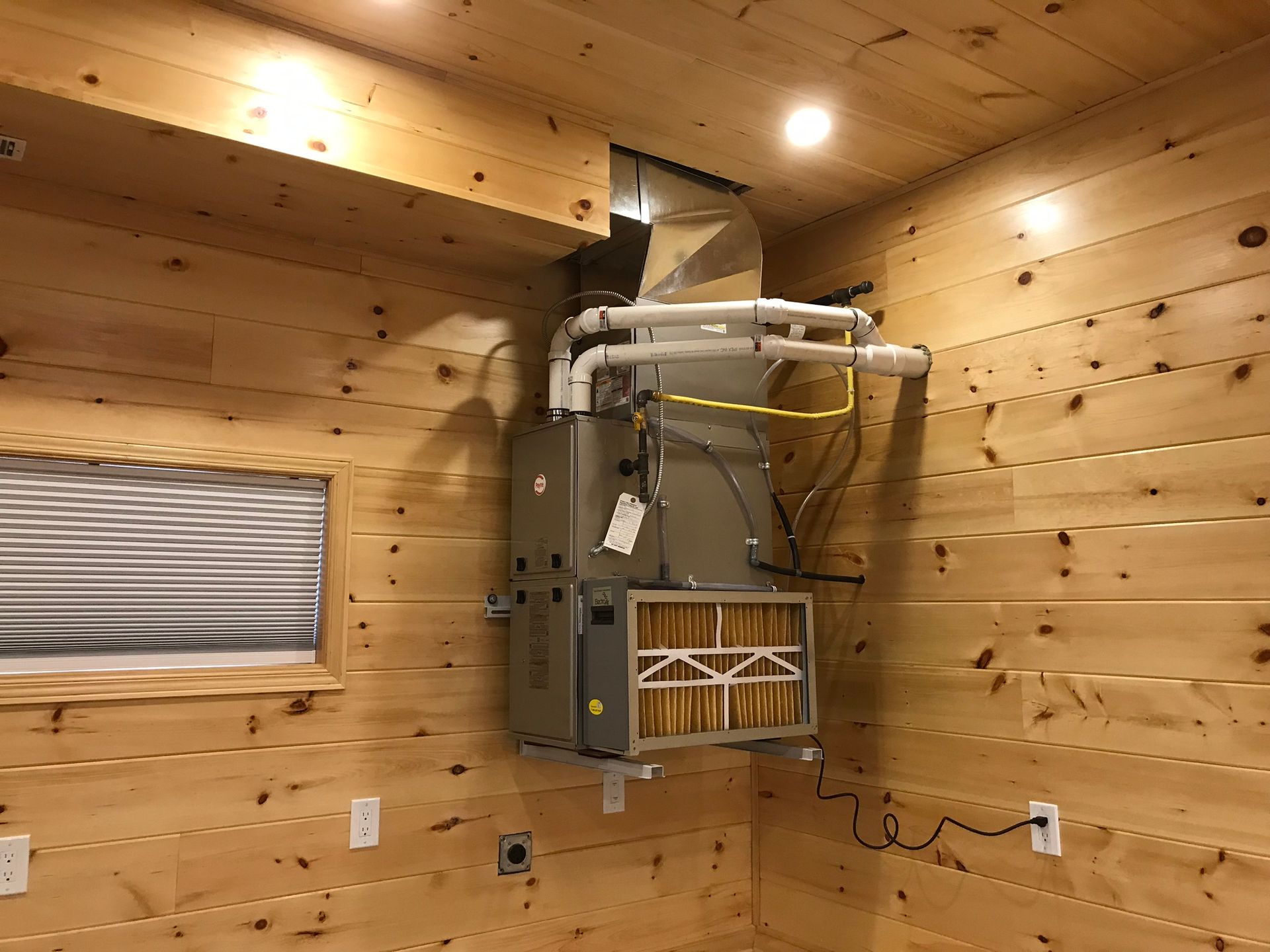 an air conditioner is hanging from the ceiling in a wooden room .