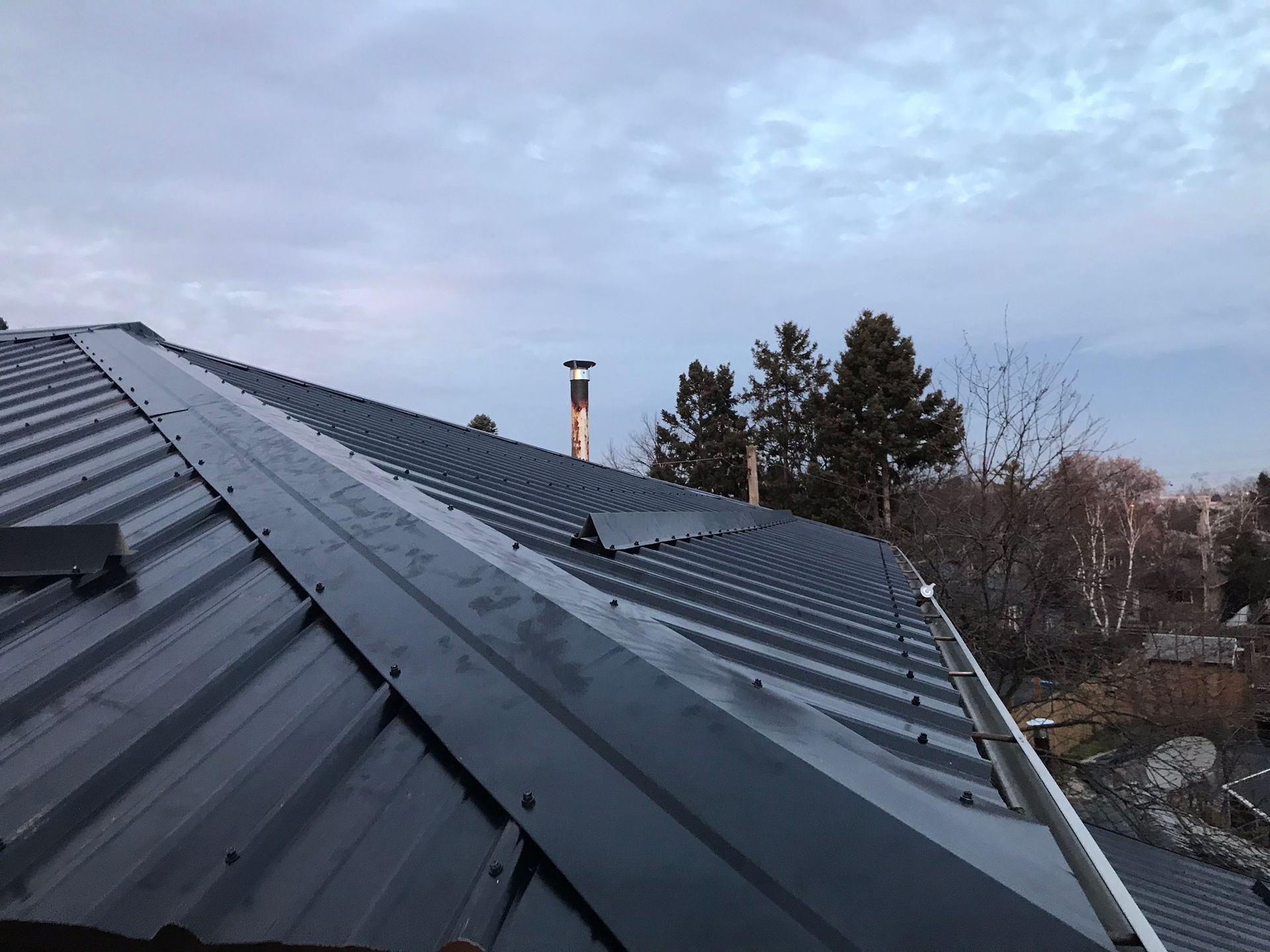 a black metal roof with a chimney on top of it .