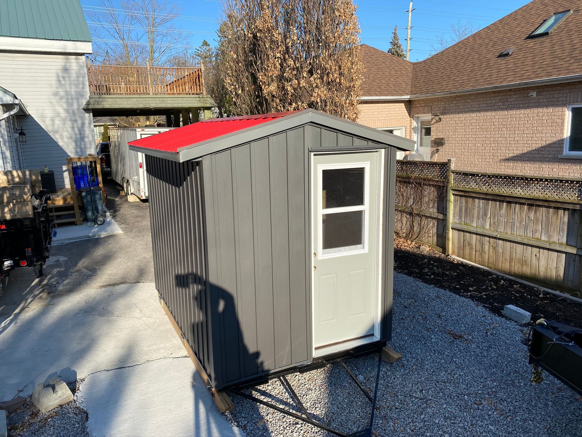 a small shed with a red roof is in the backyard of a house .