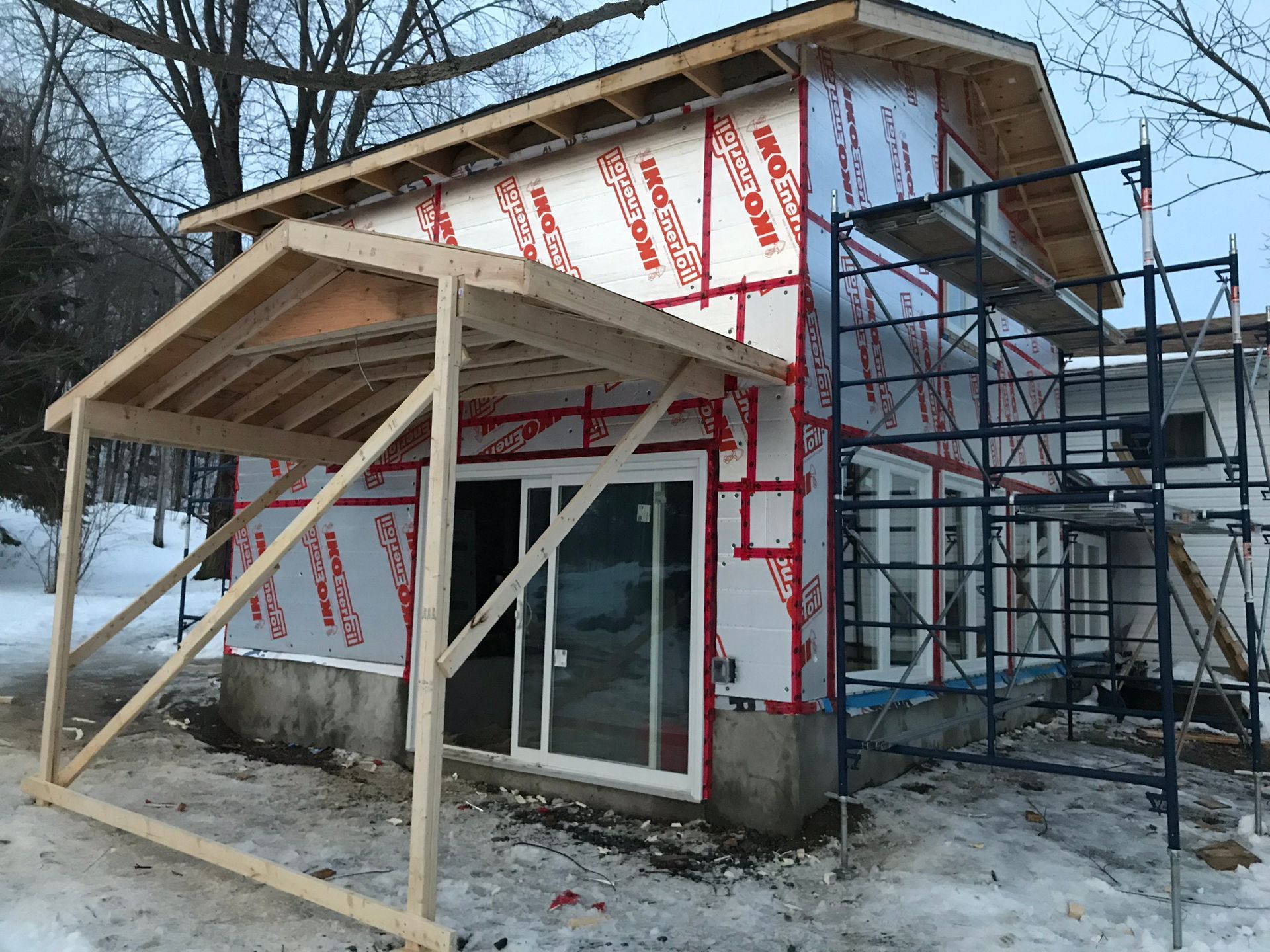 a house is being built in the snow with scaffolding around it .