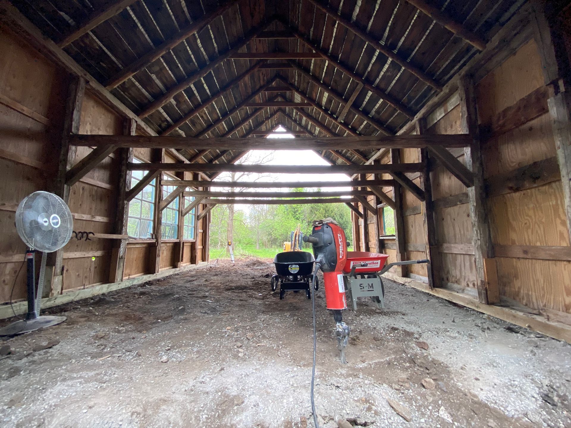 a large wooden barn with a fan and a tractor inside of it .