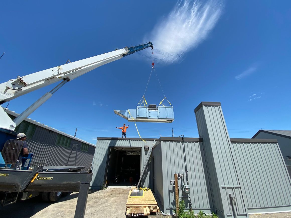 a crane is lifting a large piece of metal over a building .