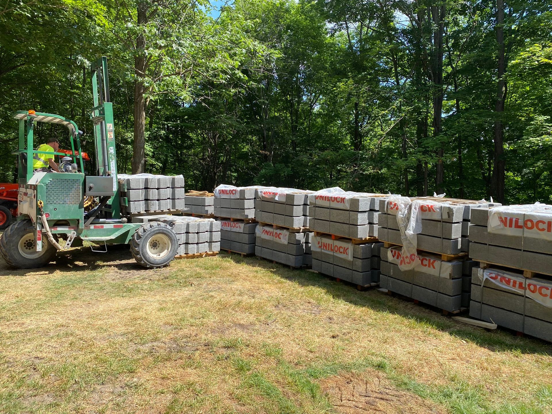 a tractor is carrying a stack of bricks in a field .